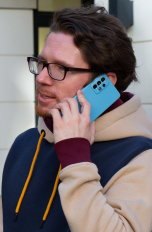 Eine Person h&auml;lt sich ein Samsung Galaxy A52S ans Ohr, um zu telefonieren.