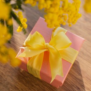 Bild von einem kleinen Geschenk, das unterhalb eines Blumenstrau&szlig;es liegt.