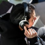 Eine Person sitzt auf einem Sessel und bedient die Touch-Schaltfl&auml;che an der rechten Ohrmuschel der Sennheiser HDB 630.